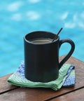 Black mug with coffee and Skinny Black Plastic Sip Stirrer Straws For Coffee And Cocktails, Seven And A Half Inch Stirrers by the pool