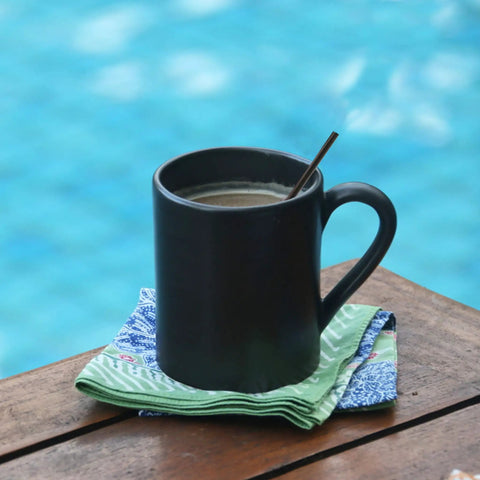 Black mug with coffee and Skinny Black Plastic Sip Stirrer Straws For Coffee And Cocktails, Seven And A Half Inch Stirrers by the pool