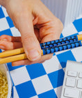 Hand holding bamboo chopsticks from Dope Retro Maze Ramen Dinnerware Set With Ceramic Bowl And Bamboo Chopsticks, 20-Ounce Noodle Bowl