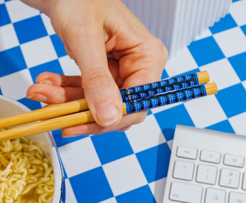 Hand holding bamboo chopsticks from Dope Retro Maze Ramen Dinnerware Set With Ceramic Bowl And Bamboo Chopsticks, 20-Ounce Noodle Bowl