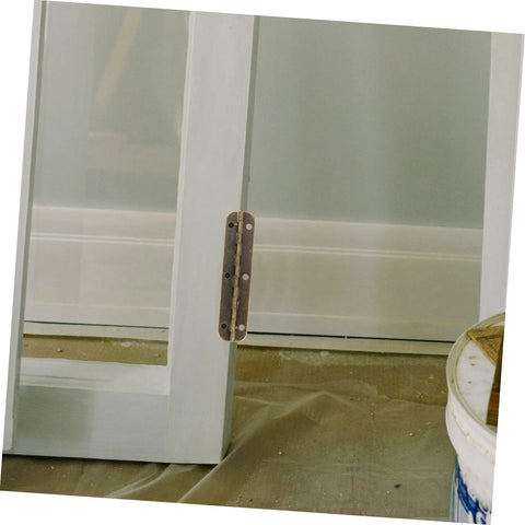 Long bronze-finish steel piano hinge installed on white cabinet door edge.