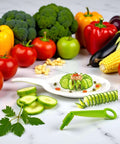 Green plastic spiral slicer with handle; cucumber spirals and sliced vegetables on a white plate