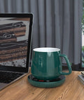 Tempered Glass Top Cup Warmer Pad With Digital Display And Auto Timer To Keep Your Morning Brew Piping Hot And Dodge The Cold Coffee Blues On Busy Weekdays, featuring a green ceramic mug on a warming pad next to a laptop.