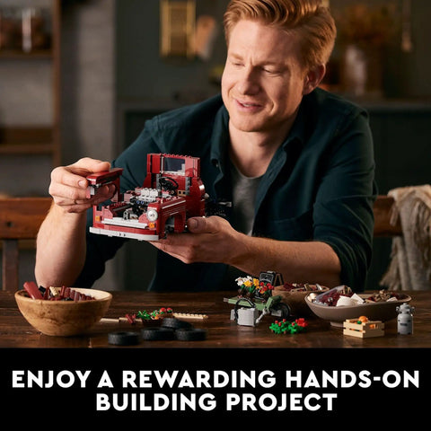 Man assembling Icons 10290 Pickup Truck Building Set For Adults with Vintage 1950s Style, showing engine and front details.