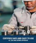 Technician inspecting a part in a factory with safety certifications displayed, emphasizing quality assurance.