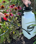 Person using 2 Gallon Lawn And Garden Sprayer For Controlling Insects And Weeds Or Cleaning Decks And Siding With Comfort Grip near flowers.