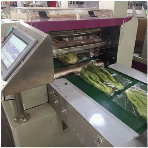 Smooth Operator Compact Horizontal Flow Pack Machine Small Shrink Wrapper Rock Solid Performance 50 To 80 Wraps Per Minute with packed greens on conveyor.