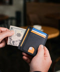 Dead Simple Minimalist Front Pocket Leather Wallet With Secure RFID Blocking For Men And Women Hella Slim Everyday Carry Low Build Cash And Card Organizer Cross Black Finish with cash and cards visible.