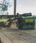 Rifle supported by TackDriver Gun Bag With One Piece Construction And Non Marring Surface For Outdoor Range And Hunting on a wooden table.