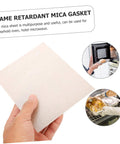 Hand holding a mica plate sheet for microwave oven use, highlighting heat insulation and flame retardant properties.