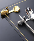 Stainless Steel Cutlery Holder Rack with gold and silver swan design on restaurant table; Durable Utensil Stand.