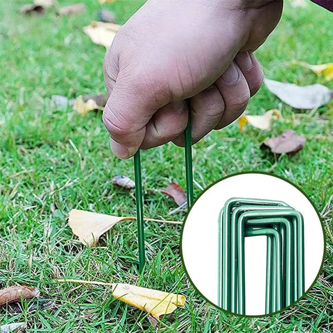 Heavy Duty Garden Stakes And Ground Anchors Set 10 Pack Galvanized U Hooks being inserted into lawn for landscape weed barrier securing