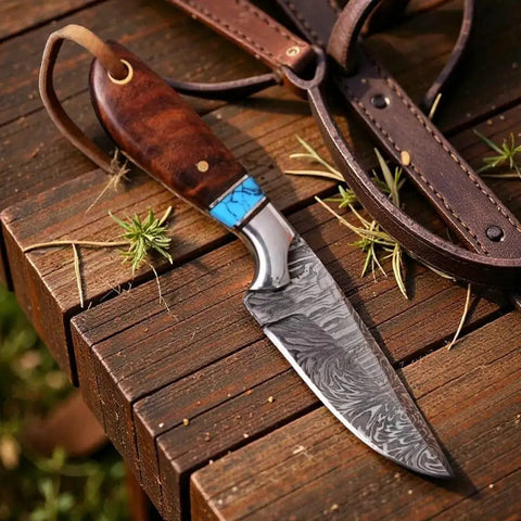 Damascus Cowboy Knife with Rosewood Handle and Leather Pancake Sheath, fixed blade on wooden table, used for outdoor survival.