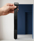 Hand holding a black strap from Sectional Couch Connector Straps 30 Pack With Hook And Loop Fasteners To Keep Modular Sofas Stable For Home And Office Use