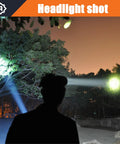 Silhouette of person using Ultra Bright Rechargeable Headlamp With Long Range LED Spotlight illuminating trees at night.