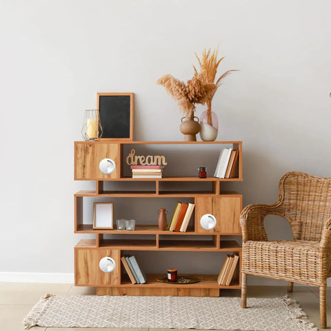 Living room with wooden bookshelf and decorative items, including a rattan chair and a vase with dried flowers.