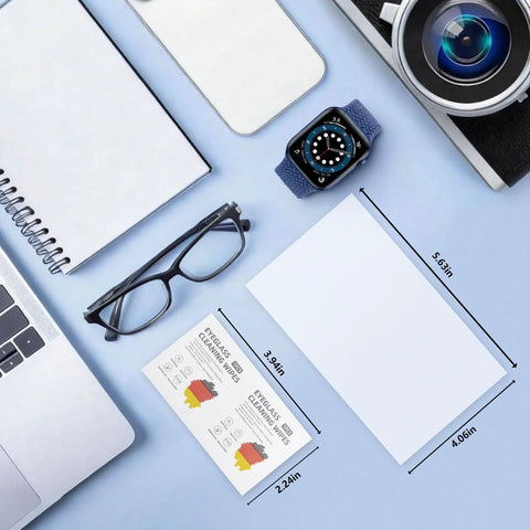 Eyeglass lens wipes; pre-moistened, individually wrapped, overhead view with glasses, notebook, and camera on blue desk.