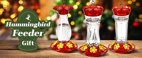 Three red and clear hummingbird feeders with floral designs displayed on a wooden surface, ideal for garden decoration.