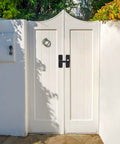 White double gate with 2 Pack Heavy Duty 180 Degree Barn Door Lock Hardware With Thickened Flip Latches, matte black finish, installed outdoors.