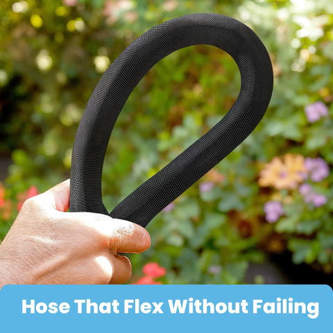 Close-up view of a black braided garden hose held in a hand in a garden setting.