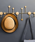 Snag Free Wall Mount Coat Hooks Built From Tough Wrought Iron With Funky Dot Designs And Relaxed Nordic Flair To Keep Your Daily Grind And Hallway Gear Tidy, featuring gold hooks with a straw hat.