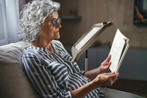 Senior woman reading with Bronze Floor Magnifier Lamp With 8x10 Inch Shade 3x Magnification Built In LED Lighting Full Page View.