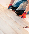 Person installing flooring wearing heavy duty knee pads for work and home use with double gel comfort extra thick foam adjustable non slip straps.