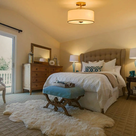 13 Inch Mid Century Modern Flush Mount Ceiling Light With Cream White Fabric Shade And Antique Brass Finish 3 Light Drum Fixture For Bedroom Dining Room Foyer And Kitchen, shown in a cozy bedroom setup