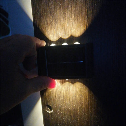 Person holding one of the Up And Down Solar Fence Lights 2 Pack Waterproof Solar Step Lights Warm White Outdoor Deck Lighting Easy Install