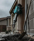 Badass Heavy Duty Eighty Volt Brushless Cordless Breaker Hammer displaying knockout chisel, set against a concrete slab.