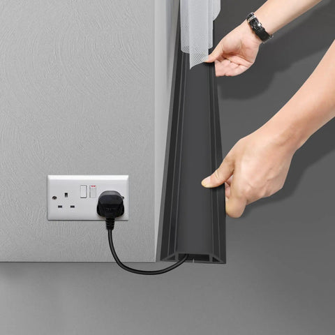Person installing Heavy Duty PVC Floor Cord Cover For Wires And Cables, Easy Unroll Floor Cable Management Ramp, Black, on floor near outlet.