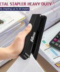 Hand using Beefy Heavy Duty Metal Stapler 50 Sheet Capacity With 1750 Staples And Stapler Remover Full Strip Desk Stapler No Jam Non Slip For Office And Classroom Black on desk stack.