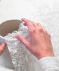 Hands wrapping ceramic vase with Heavy Duty Large Bubble Cushioning Wrap For Moving And Shipping, 60 Ft Perforated Bubble Roll.