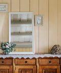 Wooden dresser with decorative mirror and floral arrangement on wall
