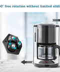 Eight Pack Countertop Appliance Sliders With Self Adhesive Rollers For Coffee Makers Air Fryers Stand Mixers And Blenders 360 Degree Rotating Mini Sticky Wheels With Stainless Steel Balls Black shown under a coffee maker demonstrating 360° rotation.