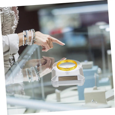 Galpada Solar Powered Jewelry Display Stand With Electric Rotating Turntable For Bracelets And Watches Plus Earrings Store Office Counter Shelf Rack Natural Light Battery Backup Smooth Spin Showcase showcasing a gold bracelet.