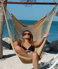 Ultra Comfy 48 Inch Polyester Hammock Chair With Built In Footrest shown in use on a beach, highlighting its tan color and ergonomic design.