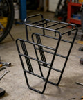 Aluminum gravel bike front carrier rack for bikepacking adventures displayed in a workshop setting
