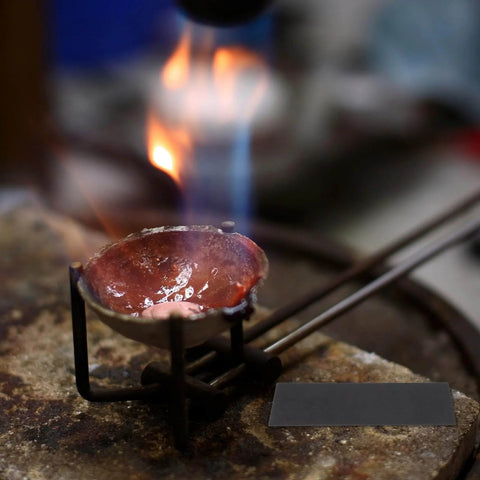 Molten metal in a crucible under flame with graphite block ingot plate for vacuum furnaces, electrolysis, and electroplating visible