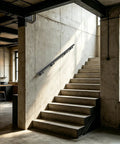 Heavy Duty Flush Wall Mount Stair Railing In Corrosion Resistant Stainless Steel With Matte Black Finish Six Foot Length mounted on indoor concrete stairs.