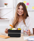 Woman smiling with Adult Bento Box With Compartments, 47oz Stackable Japanese Style Rectangle Lunch Container with utensils on desk.