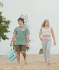 Two people walking on beach, person holding Two Pack Ultra Waterproof Wet Dry Bags With Dual Zippered Pockets for swim gear.