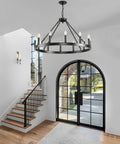 Top Tier 32 Inch Black Wagon Wheel Chandelier With 12 Lights above staircase in foyer with natural light.