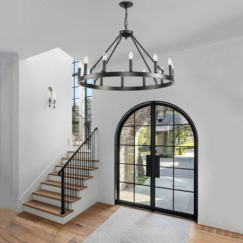 Top Tier 32 Inch Black Wagon Wheel Chandelier With 12 Lights above staircase in foyer with natural light.
