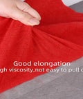 Hand lifting red fabric to show adhesion of Heavy Duty Double Sided Carpet Tape For Rugs And Area Mats 2 Inch Wide By 21.9 Yards Strong Adhesion