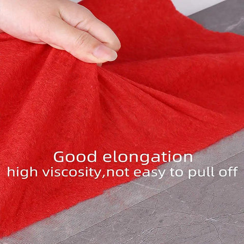 Hand lifting red fabric to show adhesion of Heavy Duty Double Sided Carpet Tape For Rugs And Area Mats 2 Inch Wide By 21.9 Yards Strong Adhesion