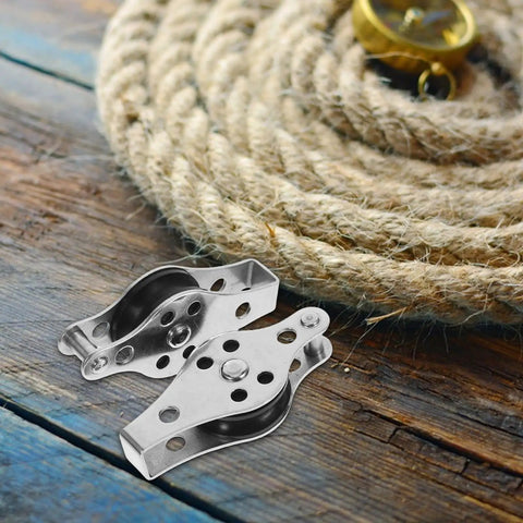 Stainless Steel Boat Pulley Wheel 2 Pack For Kayaks And Sailboats, resting on wooden surface next to coiled rope.