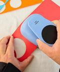Using the XL 3 Inch Circle Punch For Paper Crafts And Scrapbooking Easy To Use Spring Action Lever Cutter, blue, to cut red paper.