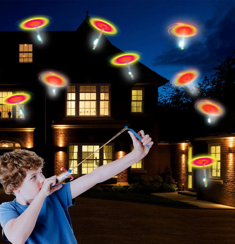 Child using slingshot with 60 Pack LED Arrow Helicopter Slingshot Toys for Kids against night sky, Electric LED Flying Copters in motion.
