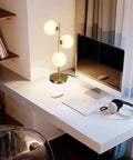 Three Light Brass Bedside Lamp With Mid Century Globe Shade In White And Gold For Reading In Office Living Room Dresser And Bathroom G9 Base Perfect Retro Modern Vibe And Cozy Nightstand Ambience on a desk